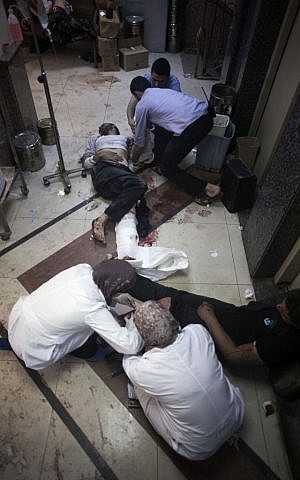 FILE - In this Thursday, Oct. 11, 2012, file photo, nurses and doctors treat men, wounded by Syrian Army shelling, at Dar al-Shifaa hospital in Aleppo, Syria. (Manu Brabo, File/AP) 
