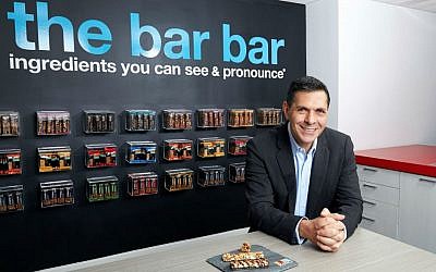 Daniel Lubetzky in the kitchen area of the Kind Snacks office in New York City with the many flavors of his company's bars on display. (Poon Watchara-Amhaiwan/via JTA)