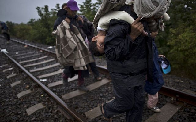 A 10-year-old Syrian migrant is carried on the back of her father as they make their way along a railway track after crossing the Serbian-Hungarian border near Roszke, southern Hungary. (AP/Muhammed Muheisen)
