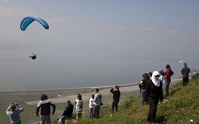 People watch a paraglider near the Golan Heights in 2009. (Matanya Tausig/Flash 90)