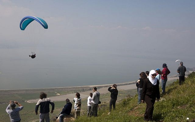People watch a paraglider near the Golan Heights in 2009. (Matanya Tausig/Flash 90)