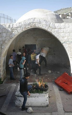 Masked Palestinian youth burn tires and throw stones in Joseph's Tomb during clashes with Israeli troops nearby, in the West Bank city of Nablus in April 2011. Palestinians shot and killed one Israeli and wounded two others on April 24, 2011 near Joseph's Tomb. (Issam Rimawi/Flash90) 