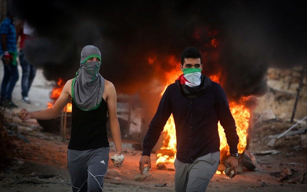 Palestinian protesters throw stones and burn tires during clashes with Israeli security forces close to the Israeli checkpoint of Hizma in the West Bank, September 30, 2015 (Flash90) Palestinian protesters throw stones and burn tires during clashes with Israeli security forces close to the Israeli checkpoint of Hizma in the West Bank, September 30, 2015 (Flash90)