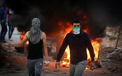 Palestinian protesters throw stones and burn tires during clashes with Israeli security forces close to the Israeli checkpoint of Hizma in the West Bank, September 30, 2015 (Flash90)
