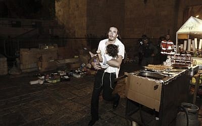 A Jewish man carries a baby injured in a stabbing attack in the Old City of Jerusalem on October 3, 2015. The terrorist was shot down by police. (Yonatan Sindel/Flash90)