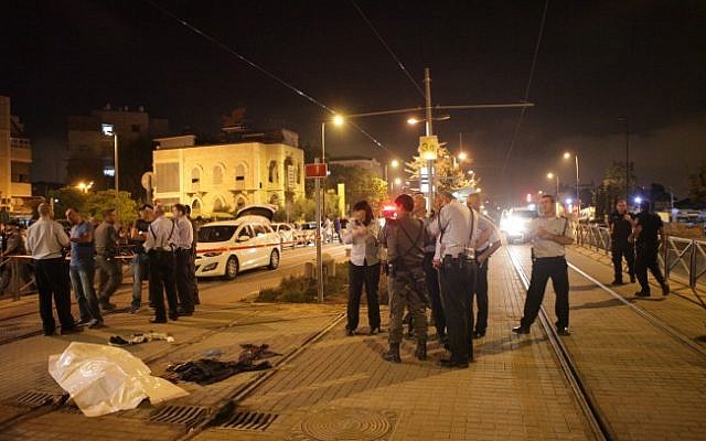 Israel Police officers stand near the body of Fadi Aloon, a Palestinian who allegedly stabbed a 15-year-old boy outside the Old City of Jerusalem, before being shot and killed by police early Sunday morning, October 4, 2015. (Flash90)