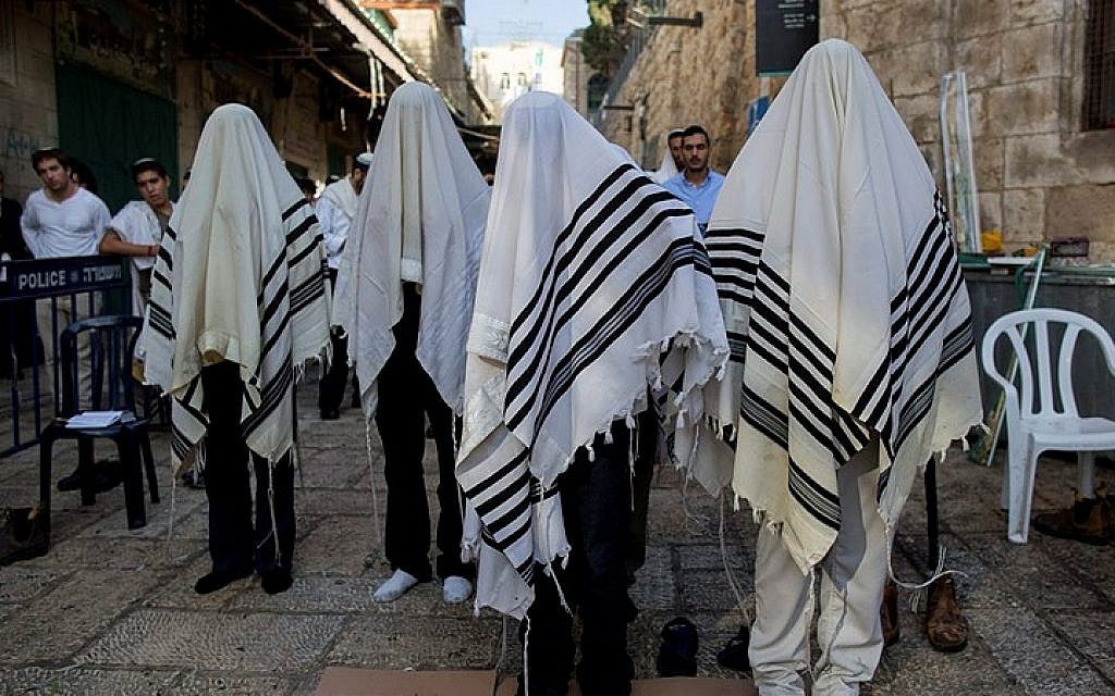 Jewish men pray at the site of where two Israeli men, one in his 40s and the other in his 20s, died of their wounds Saturday night after being stabbed in Jerusalem’s Old City in a terror attack, October 4, 2015. (Yonatan Sindel/Flash90)