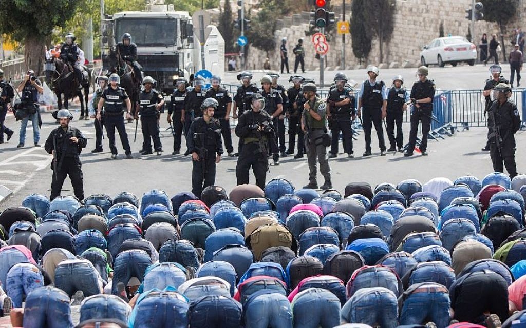 Palestinians pray as Israeli policemen watch in the East Jerusalem neighborhood of Wadi al-Joz, October 9, 2015. Israeli police declared an age limit on Friday for Palestinians wanting to enter the Old City, only allowing males above the age of 45 and all females to enter. (Yonatan Sindel/Flash90) Palestinians pray as Israeli policemen watch in the East Jerusalem neighborhood of Wadi al-Joz, October 9, 2015. Israeli police declared an age limit on Friday for Palestinians wanting to enter the Old City, only allowing males above the age of 45 and all females to enter. (Yonatan Sindel/Flash90)