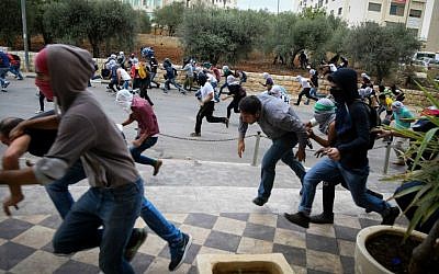Palestinian protesters hurling stones at Israeli troops (not seen) during riots near the Jewish settlement of Bet El, near the West Bank city of Ramallah, October 10, 2015. (Flash90)