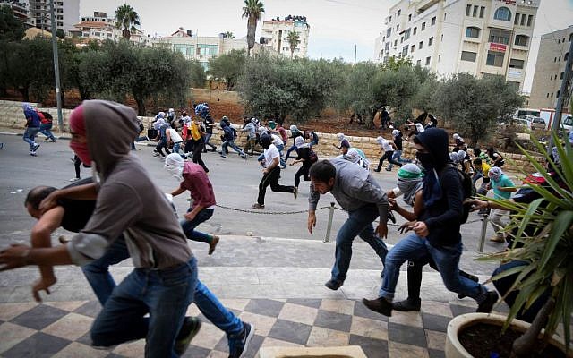 Palestinian protesters hurling stones clash with Israeli troops (not seen) during riots by the Jewish settlement of Bet El, near the West Bank city of Ramallah, October 10, 2015 (Flash90) Palestinian protesters hurling stones clash with Israeli troops (not seen) during riots by the Jewish settlement of Bet El, near the West Bank city of Ramallah, October 10, 2015 (Flash90)