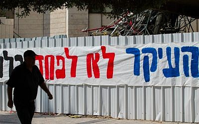 Jerusalemites walk by a large sign reading 'The main thing is not to fear at all.' posted in downtown Jerusalem following the recent wave of terror attacks (Nati Shohat/Flash 90)