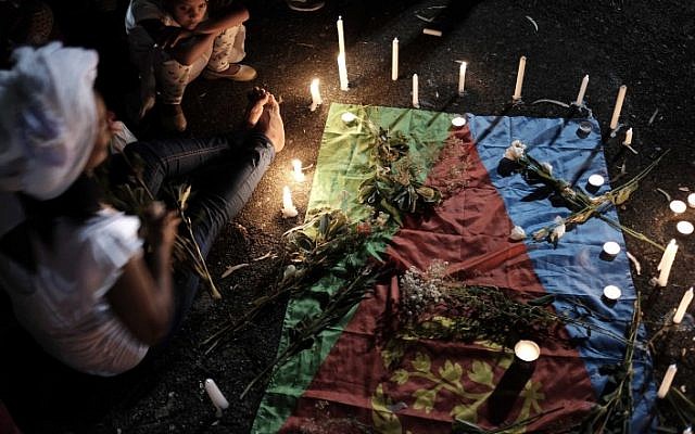 Mourners light candles on an Eritrean flag as they eulogized Haftom Zarhum on October 21, 2015. (Tomer Neuberg/Flash90)