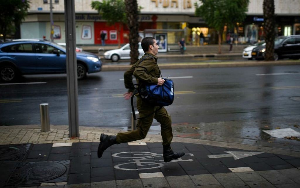 An Israeli soldier runs in heavy rains and strong winds as a thunderstorm hits Tel Aviv, October 25, 2015. (Ben Kelmer/Flash90)