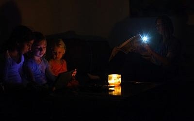 An Israeli family sits in the darkness in their home, near the Israeli town of Netanya, a day after a powerful rainstorm hit Israel on October 15, 2015, downing trees and hundreds of power lines. (Chen Leopold/FLASH90)