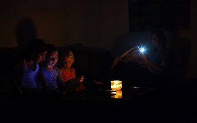 An Israeli family sits in the darkness of their home during a power outage, near the Israeli town of Netanya, on October 26, 2015. (Chen Leopold/FLASH90) An Israeli family sits in the darkness of their home during a power outage, near the Israeli town of Netanya, on October 26, 2015. (Chen Leopold/FLASH90)