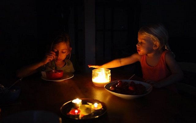 An Israeli family sits in the dark in their home near the Israeli coastal city of Netanya, a day after a powerful rainstorm hit Israel, downing trees and hundreds of power lines, Monday night, October 26, 2015 (Chen Leopold/FLASH90)