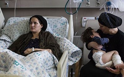 In this Monday, Oct. 12, 2015 photo, Odel Bennett lies on a bed as her mother Miriam Gal holds Odel's 2-year-old son Natan at the Hadassah Medical Center in Jerusalem (AP/Tsafrir Abayov)