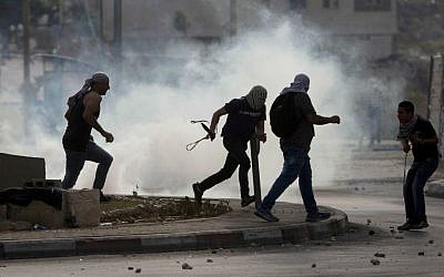 Palestinians run from tear gas during clashes with Israeli troops near Ramallah, West Bank, Monday, Oct. 12, 2015. (AP Photo/Majdi Mohammed)
