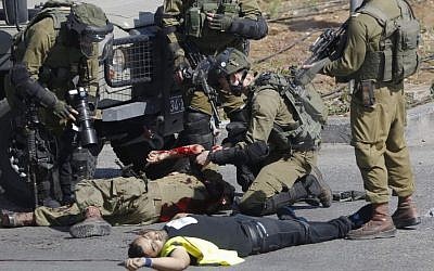 Israeli soldiers treat a wounded comrade after he was stabbed by a Palestinian, seen on the ground, during clashes in Hebron, West Bank Friday, Oct. 16, 2015. The Palestinian man wearing a yellow "press" vest and a T-shirt identifying him as journalist stabbed and wounded an Israeli soldier in the West Bank city of Hebron on Friday before being shot dead by troops, the latest in a month-long spate of attacks. (AP/Nasser Shiyoukhi) Israeli soldiers treat a wounded comrade after he was stabbed by a Palestinian, seen on the ground, during clashes in Hebron, West Bank Friday, Oct. 16, 2015. The Palestinian man wearing a yellow "press" vest and a T-shirt identifying him as journalist stabbed and wounded an Israeli soldier in the West Bank city of Hebron on Friday before being shot dead by troops, the latest in a month-long spate of attacks. (AP/Nasser Shiyoukhi)