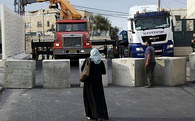Palestinians watch a wall being built between Palestinian and Jewish neighborhoods in Jerusalem Sunday, Oct. 18, 2015. (AP Photo/Mahmoud Illean)