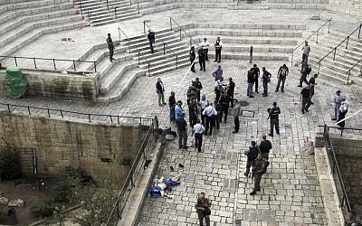 Israeli police stand near the body of a Palestinian who, according to the police, stabbed two police officers at the Damascus Gate of Jerusalem's Old City, Saturday, Oct. 10, 2015. (AP Photo/Mahmoud Illean)