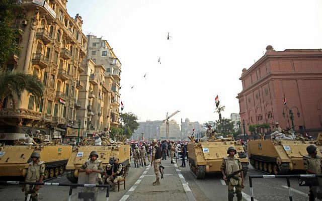In this Sunday, Oct. 6, 2013, file photo, Egyptian military helicopters fly overhead as army soldiers stand guard at an entrance to Tahrir Square, in Cairo. (AP Photo/Khalil Hamra, File) In this Sunday, Oct. 6, 2013, file photo, Egyptian military helicopters fly overhead as army soldiers stand guard at an entrance to Tahrir Square, in Cairo. (AP Photo/Khalil Hamra, File)
