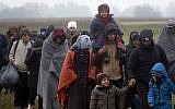 Migrants move through a field after crossing from Croatia, in Rigonce, Slovenia, Sunday, Oct. 25, 2015. (AP/Darko Bandic)