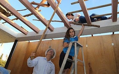 Great-grandchildren of Dov and Shoshana Kanohel, the founders of Kfar Etzion in 1943, building a sukkah, October 1, 2014. (Gershon Elinson/Flash90)