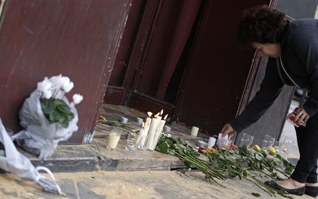 A woman leaves candles and flowers outside of the Carillon bar in the 10th district of Paris on November 14, 2015, after a series of attacks in and around the city left at least 128 people dead. (AFP PHOTO/KENZO TRIBOUILLARD)