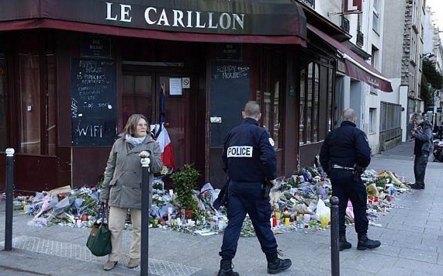 Police officers walk past flowers, notes and candles at a memorial site outside the Carillon bar, in the 10th District of Paris, for victims of the November 13 terrorist attacks in Paris, November 15, 2015. (AFP/Bertrand Guay) Police officers walk past flowers, notes and candles at a memorial site outside the Carillon bar, in the 10th District of Paris, for victims of the November 13 terrorist attacks in Paris, November 15, 2015. (AFP/Bertrand Guay)