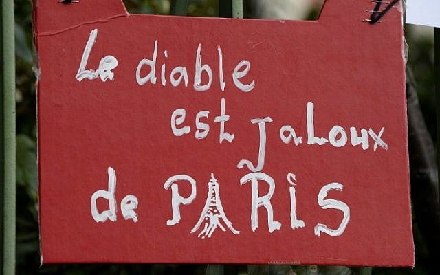 A sign which translates as "The Devil is jealous of Paris" is displayed on a fence as people gather to observe a minute of silence on November 16, 2015 at the Bataclan concert hall in Paris, to pay tribute to victims of the attacks claimed by Islamic State which killed at least 129 people and left more than 350 injured on November 13. (AFP Photo/Bertrand Guay) A sign which translates as "The Devil is jealous of Paris" is displayed on a fence as people gather to observe a minute of silence on November 16, 2015 at the Bataclan concert hall in Paris, to pay tribute to victims of the attacks claimed by Islamic State which killed at least 129 people and left more than 350 injured on November 13. (AFP Photo/Bertrand Guay)