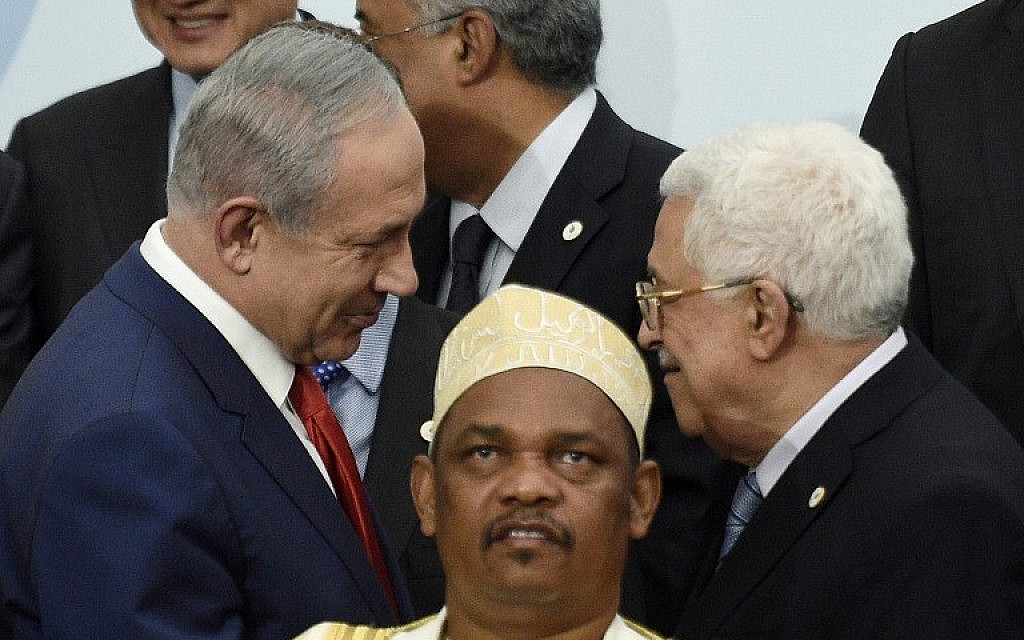 Prime Minister Benjamin Netanyahu (L) talks with Palestinian Authority President Mahmoud Abbas (R) behind Comoros' President Ikililou Dhoinine during the family photo during the COP21, United Nations Climate Change Conference, in Le Bourget, outside Paris, on November 30, 2015. (AFP PHOTO / POOL / MARTIN BUREAU)