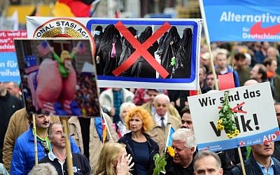 A supporter of the right-wing populist Alternative for Germany (AfD) party displays a placard during a demonstration against the German government's asylum policy in Berlin on November 7, 2015. (AFP PHOTO / JOHN MACDOUGALL)