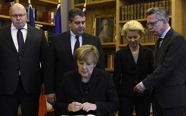 German Chancellor Angela Merkel (C) signs a condolence book for the victims of deadly attacks in Paris a day before at the French Embassy in Berlin on November 14, 2015 (Tobias Schwarz/AFP)