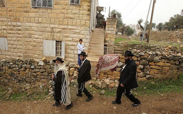 Ultra-Orthodox Jews walk past Israeli soldiers conducting a search on a Palestinian home in the West bank town of Hebron on November 7, 2015. (AFP/HAZEM BADER)