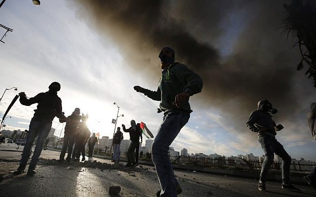 Illustrative: Palestinians throw stones at Israeli security forces during clashes in the Palestinian town of al-Bireh on the outskirts of Ramallah on November 20, 2015. (AFP Photo/Abbas Momani) Illustrative: Palestinians throw stones at Israeli security forces during clashes in the Palestinian town of al-Bireh on the outskirts of Ramallah on November 20, 2015. (AFP Photo/Abbas Momani)