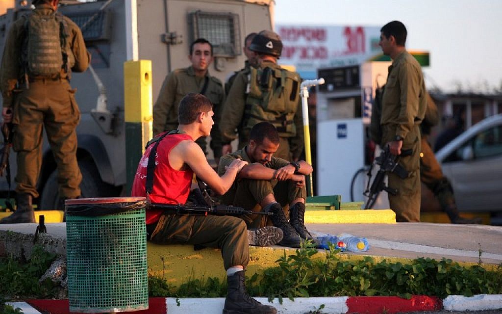 Israeli soldiers react at the scene of a stabbing attack carried out by a Palestinian man against two Israeli soldiers, killing one of them, at a gas station on a main road on the busy 443 highway on November 23, 2015. (AFP/GIL COHEN-MAGEN)