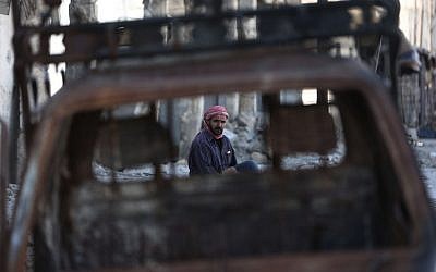 A man sits amid debris in a neighborhood heavily damaged by airstrikes in the village of Deir al-Asafir in the rebel-held region of Eastern Ghouta, on the outskirts of the Syrian capital Damascus, November 25, 2015. (Photo by AFP Photo/Amer Almohibany)