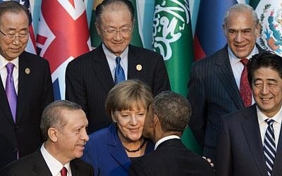 US President Barack Obama greets German Chancelor Angela Merkel, center, alongside Japanese Prime Minister Shinzo Abe, right, Turkish President Recep Tayyip Erdogan, left and other world leaders as they stand for the official family photo during the G20 summit in Antalya, Turkey, November 15, 2015. AFP/SAUL LOEB)
