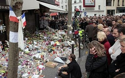 People observe a minute of silence on November 16, 2015, outside the La Belle Equipe on Rue de Charonne in the XI Arrondissement in Paris, to pay tribute to victims of the attacks claimed by Islamic State, which killed at least 129 people and left more than 350 injured on November 13, 2015. (AFP/Jacques Demarthon)