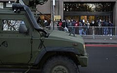 Asylum seekers queue in front of the commissioner general for refugees and stateless persons' office, which is closed because of the threat level 4, as a military vehicle drives past on November 23, 2015, in Brussels. (AFP/BELGA/DIRK WAEM)