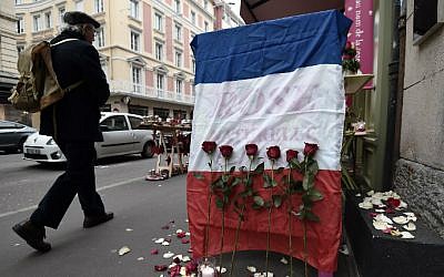 A man walks past a French national flag put outside a flower shop on November 27, 2015 in Strasbourg, eastern France, in tribute to the 130 people killed in the November 13 Paris attacks. (AFP Photo/Frederick Florin)