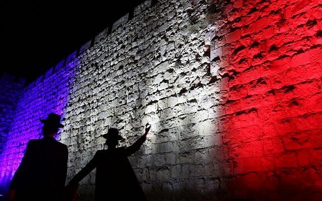 Israeli Ultra Orthodox Jewish men walk past Jerusalem's Old City Walls illuminated in red, white and blue, the colors of the French flag, in Jerusalem, November 15, 2015 (Photo by AFP Photo / Gali Tibbon)