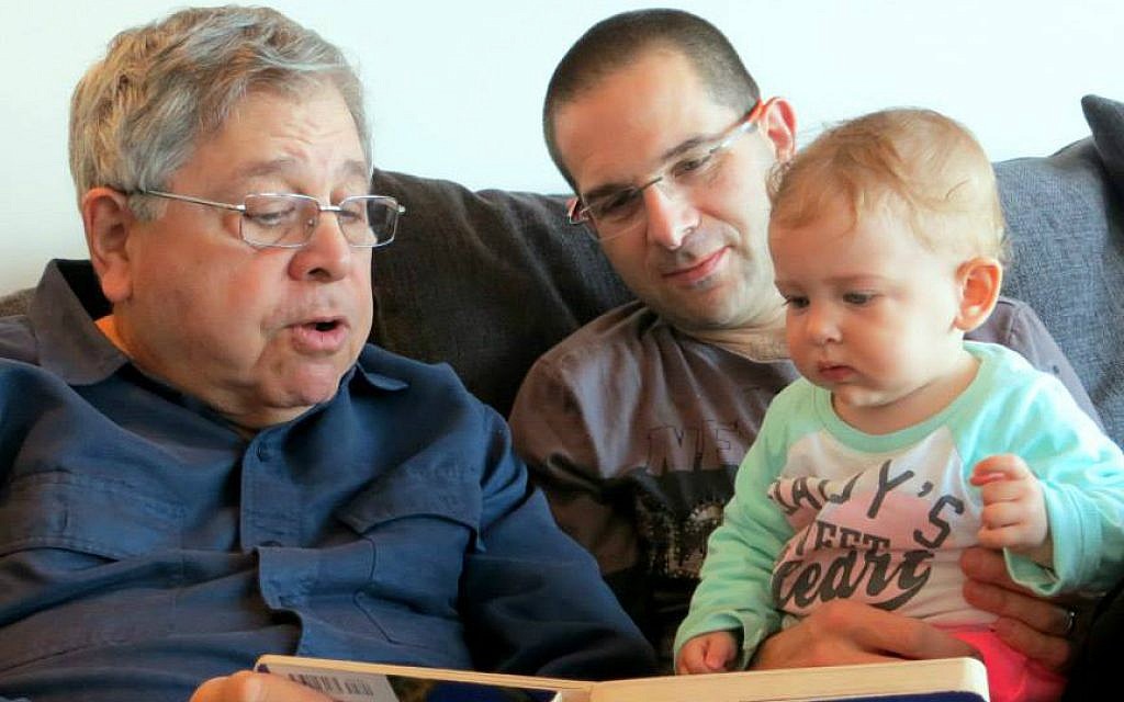 Richard Lakin (left) reads a book to his granddaughter, as his son Micah Avni looks on. January 2014. (Courtesy) Richard Lakin (left) reads a book to his granddaughter, as his son Micah Avni looks on. January 2014. (Courtesy)