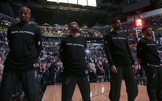 San Antonio Spurs' Tony Parker, of France, second from left, stands with teammates, from left, David West, Tim Duncan, and Kyle Anderson, during a France Moment of Silence before an NBA basketball game against the Philadelphia 76ers, Saturday, Nov. 14, 2015, in San Antonio. (AP Photo/Eric Gay)