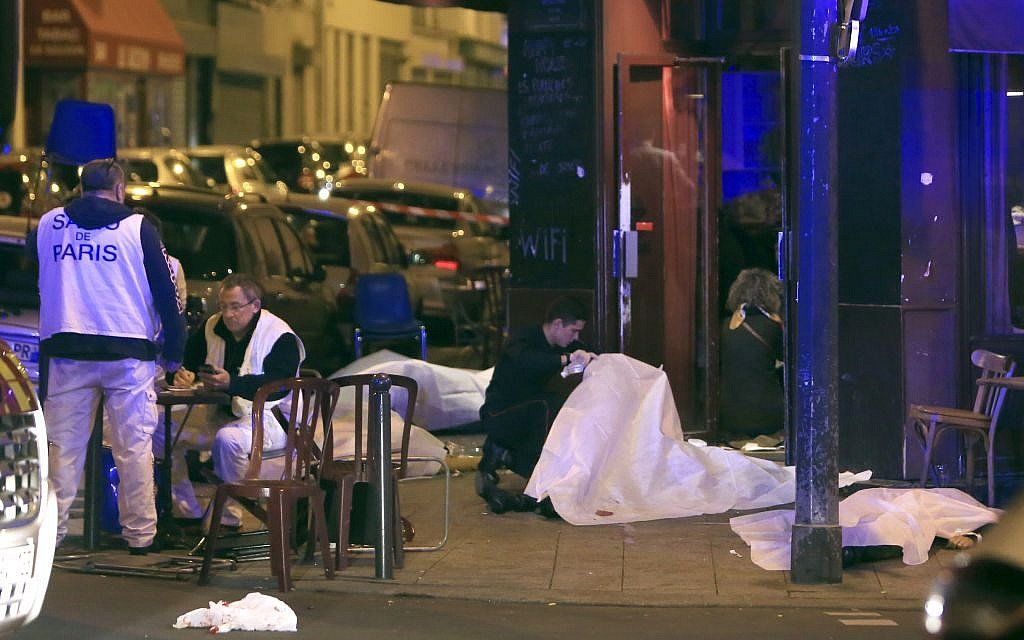Victims lay on the pavement outside a Paris restaurant, Friday, Nov. 13, 2015. Police officials in France on Friday reported multiple terror incidents, leaving many dead. (AP Photo/Thibault Camus)