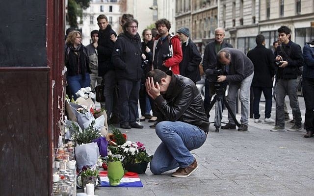 A man holds his head in his hands as he lays flowers in front of the Carillon cafe, in Paris, Saturday, Nov.14, 2015. (AP Photo/Thibault Camus) A man holds his head in his hands as he lays flowers in front of the Carillon cafe, in Paris, Saturday, Nov.14, 2015. (AP Photo/Thibault Camus)