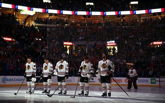Members of the Chicago Blackhawks pause for a moment of silence in honor of the victims of the Paris attacks before the start of an NHL hockey game against the St. Louis Blues Saturday, Nov. 14, 2015 in St. Louis. (AP Photo/Jeff Roberson)