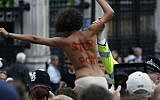 British police officer arrests an activist from FEMEN, a group opposed to Female Genital Mutilation (FGM), during a protest opposite the Houses of Parliament in central London on July 7, 2014. (AP Photo/Lefteris Pitarakis, File)