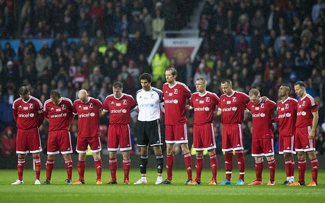 Players stand for a minute silence for the victims of the Paris attacks before the Unicef Match for Children charity football match between a Great Britain and Ireland team and a Rest of the World team at Old Trafford Stadium, Manchester, England, Saturday, Nov. 14, 2015. (AP Photo/Jon Super)